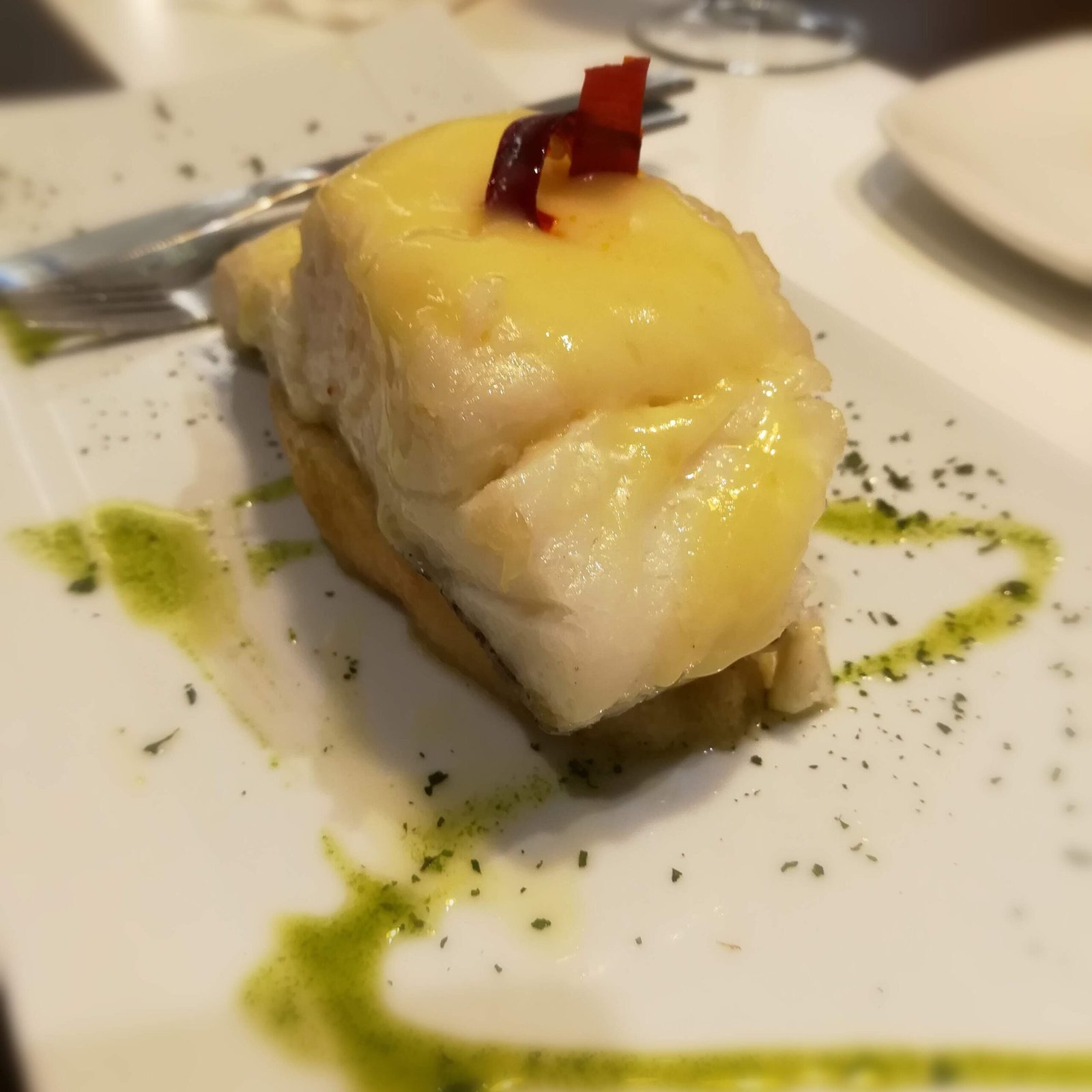 A tapas serving of bacalao al pil pil sits on a countertop of a restaurant