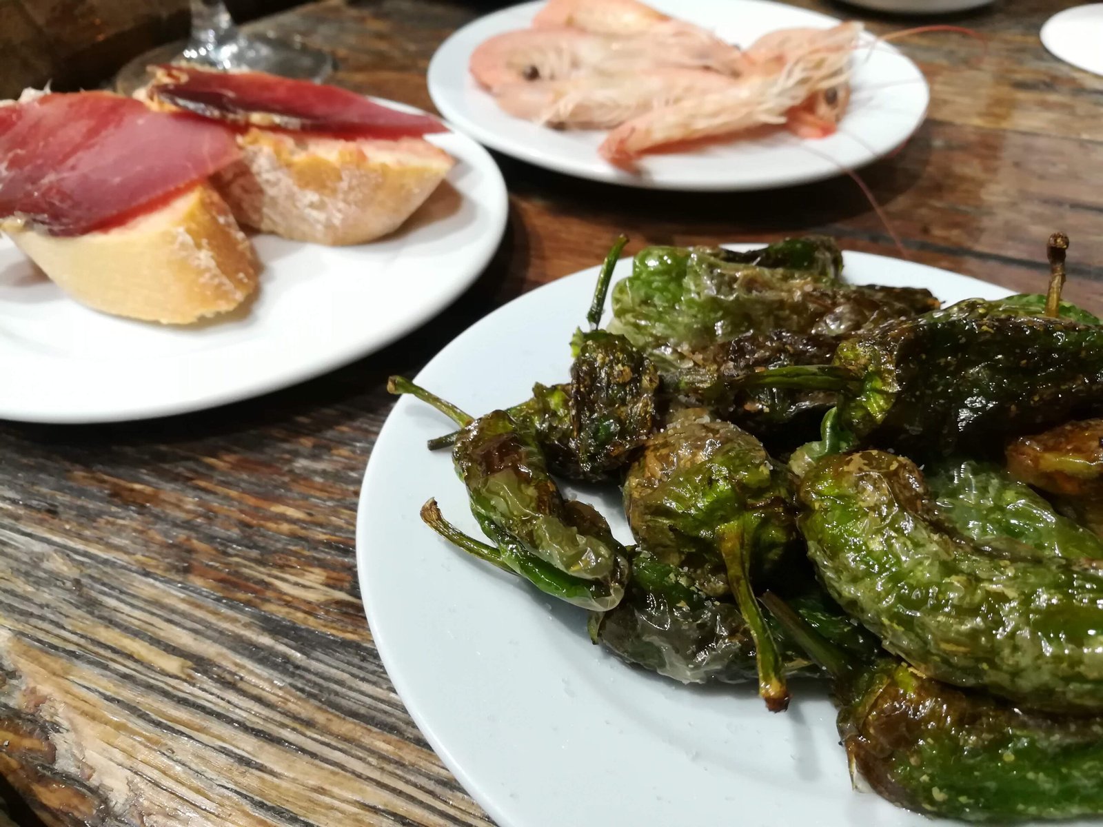 Spanish tapas plates of ham, pimientos padron, and prawns