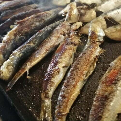 a large skillet with lots of anchovies being frid with lots of salt and olive oil