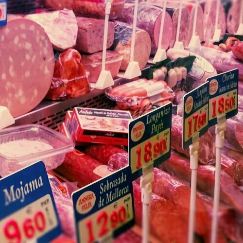 A meat counter displaying many various cuts of meat in a market setting