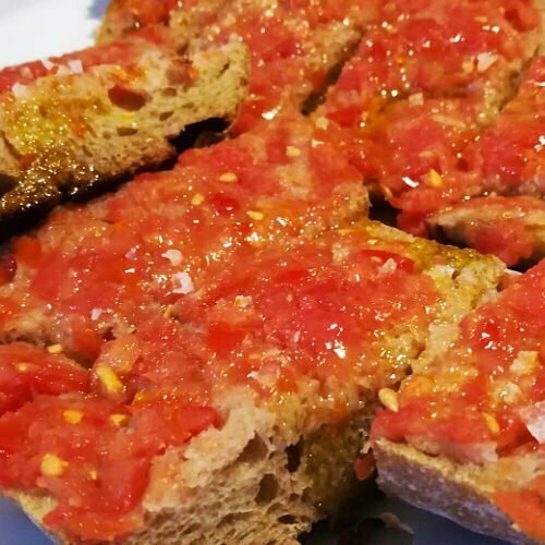 Close up photo of the Spanish dish.,  Pan con tomate. Lightly fried and crushed tomato spread onto lightly. toasted bread with lots of salt and olive. oil added.  