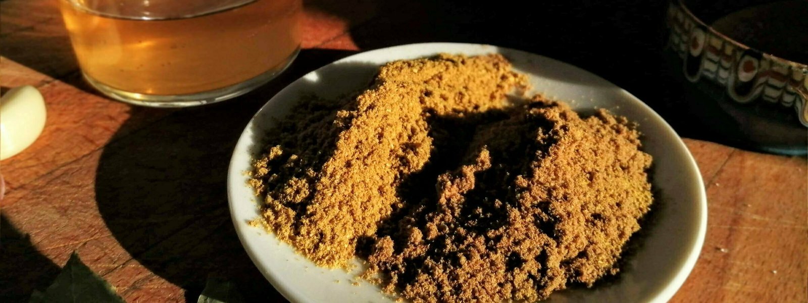 A plate of Ground corriander spice sits on a kitchen worktop with a small glass of olive oil sitting in the background