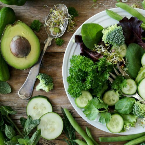 A bowl filled with green salad mix sits beside an avocado and other plant pbased foods featured in the Mediterranean diet