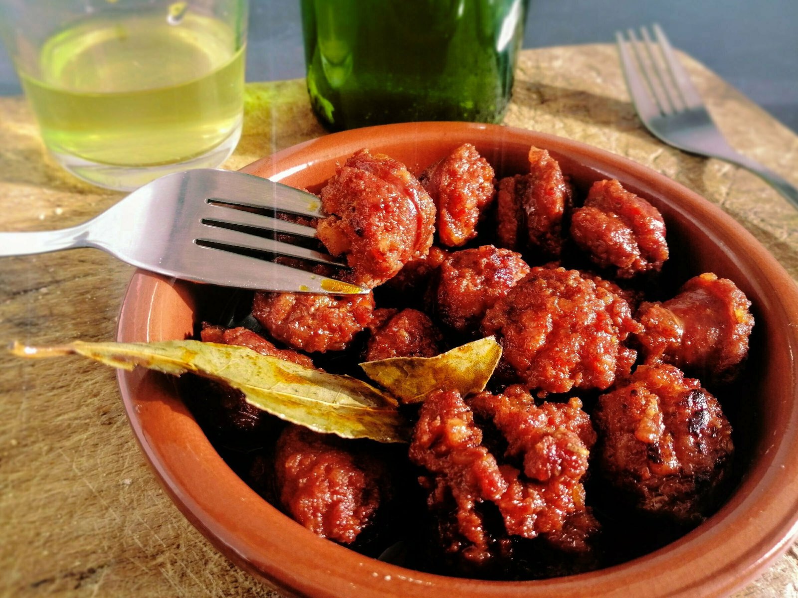 An earthenware dish sits filled with the classic tapas dish of Chorizo cooked in cider.