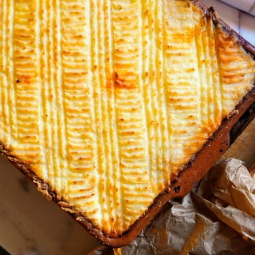 A tray of Spanish seafood pie sits beside a baguette of fresh bread