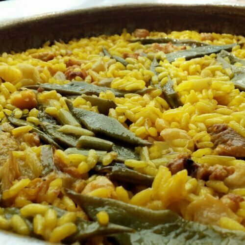 A large pan of paella valencia sits on a counter top
