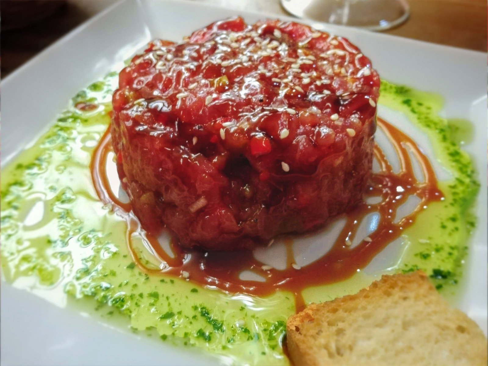 A plate of tartar de atun sits on a bar counter waiting to be served. 