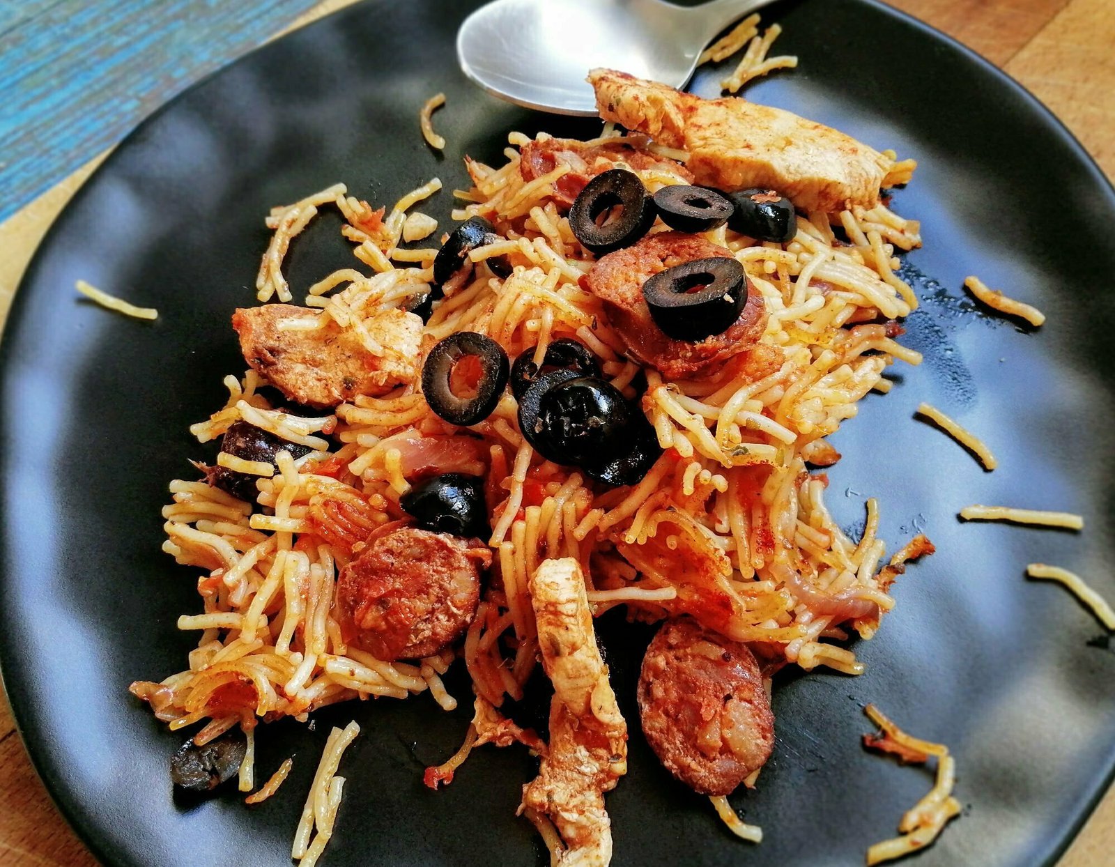 chicken-chorizo-pasta-plated a plate of chicken and chroizo pasta is served with some black olives sprinkled on top