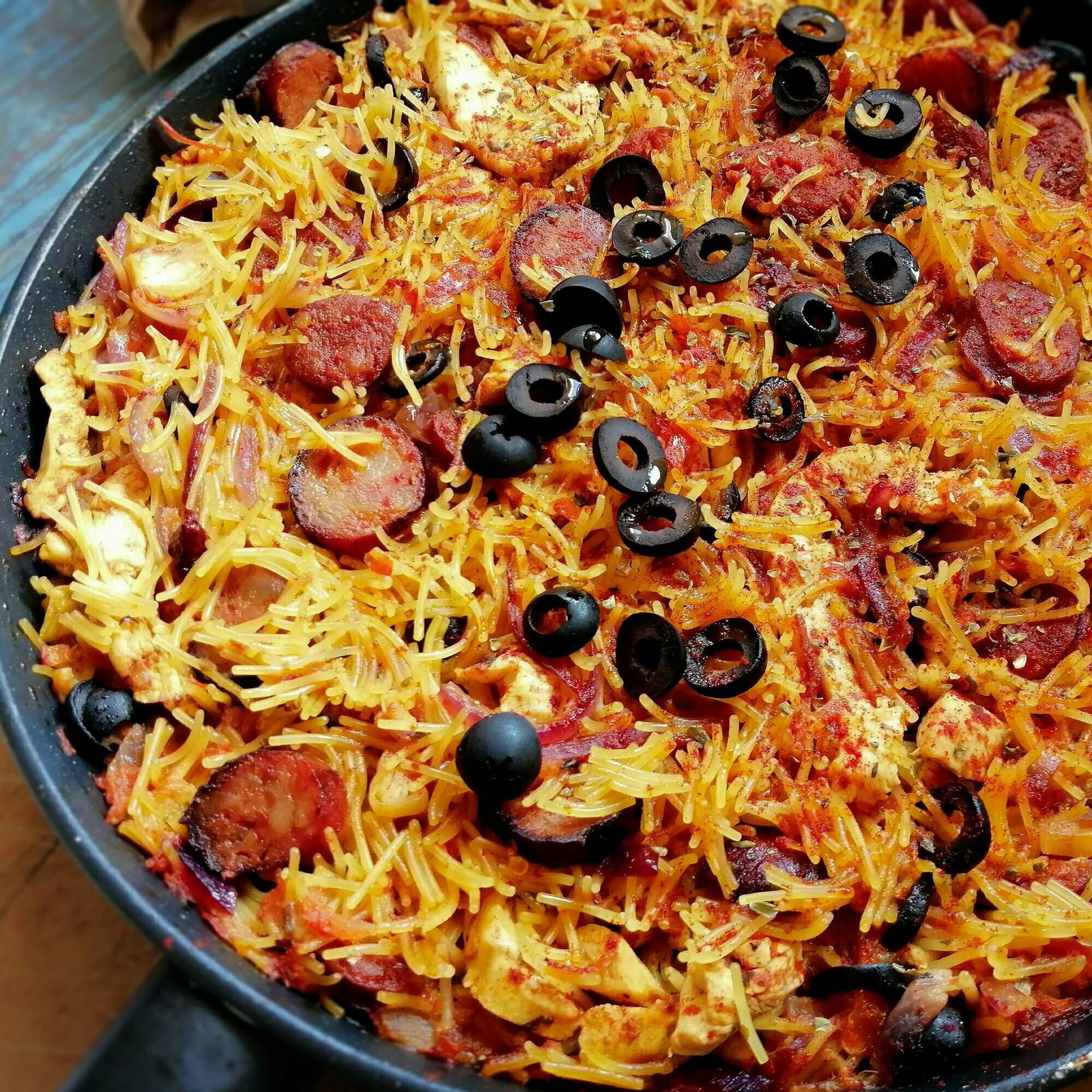 A large pan of chicken and chorizo pasta sits on a kitchen countertop waiting to be served. 