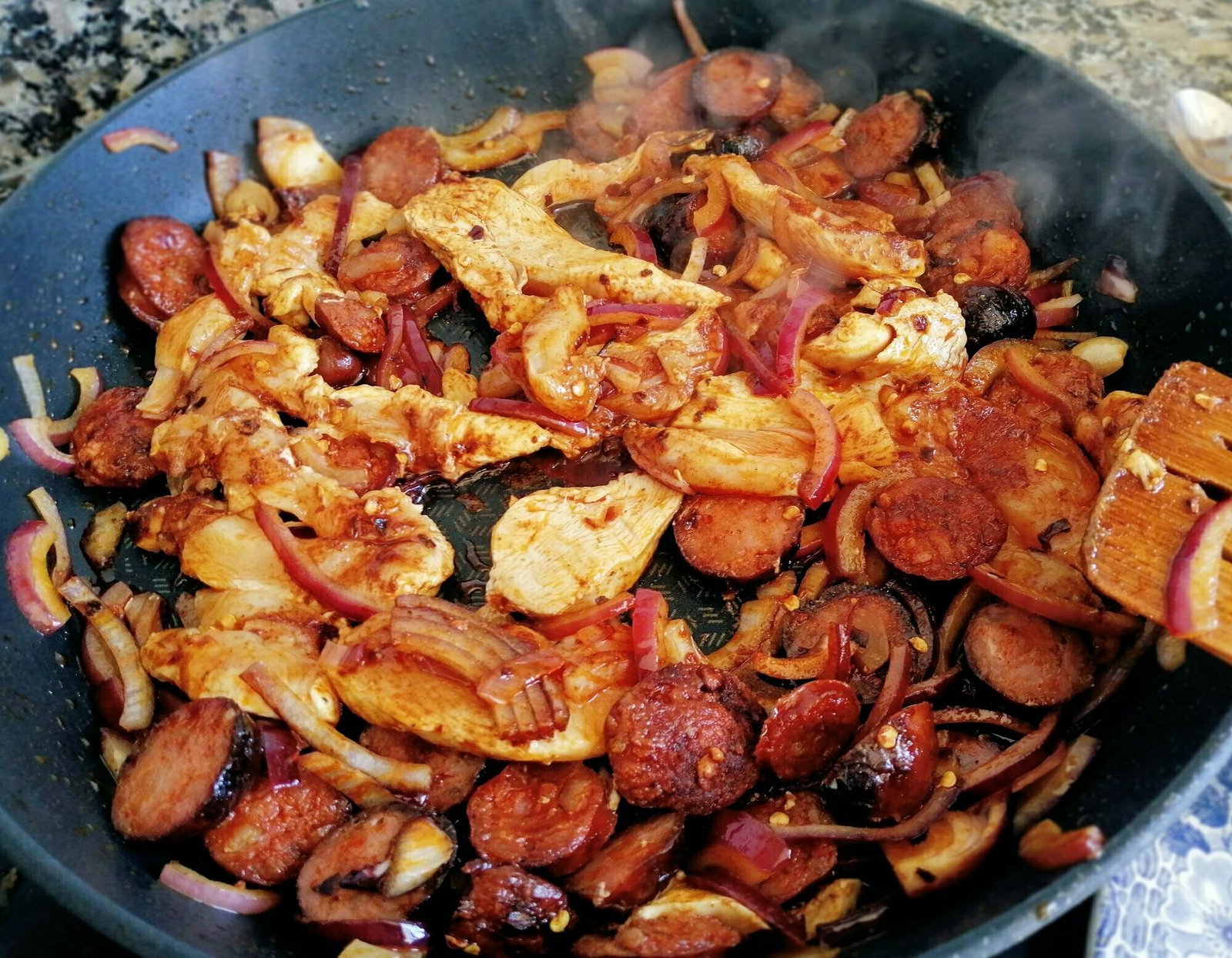 Chicken, chorizo, and onion cooks in a large frying pan