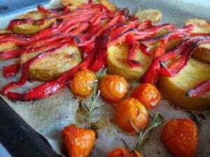 a large baking tray of roasted veggies sits on a table waiting to be served