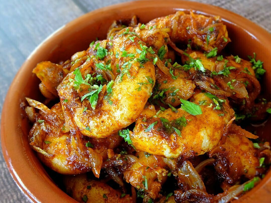 a earthenware dish sits filled with sizzling garlic shrimp called gambas al ajillo in Spanish