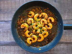 a large frying pan sits on a wooden counter that's topped with garlic shrimp (called gambas al ajillo in Spanish)