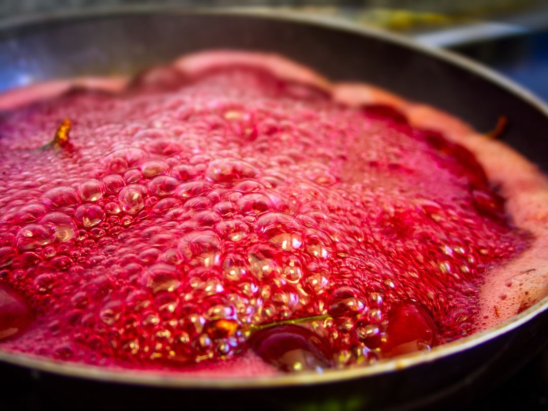 a pan of simmering cherries bubbles away on a stovetop