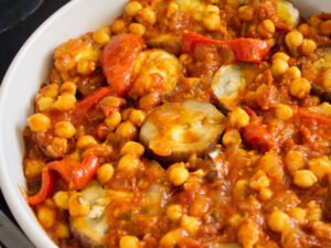 layers of roasted eggplant sit amongst a tomato and chickpea sauce in a large white casserole dish