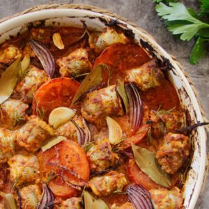 A large casserole dish sits with fish tomato red onion and romesco sauce