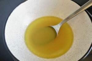 a small white bowl with a black rim olds some salad dressing