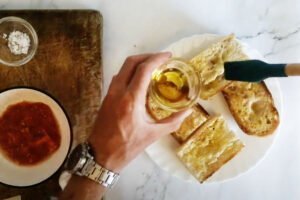 Some golden slices of bread are being brushed with some olive oil