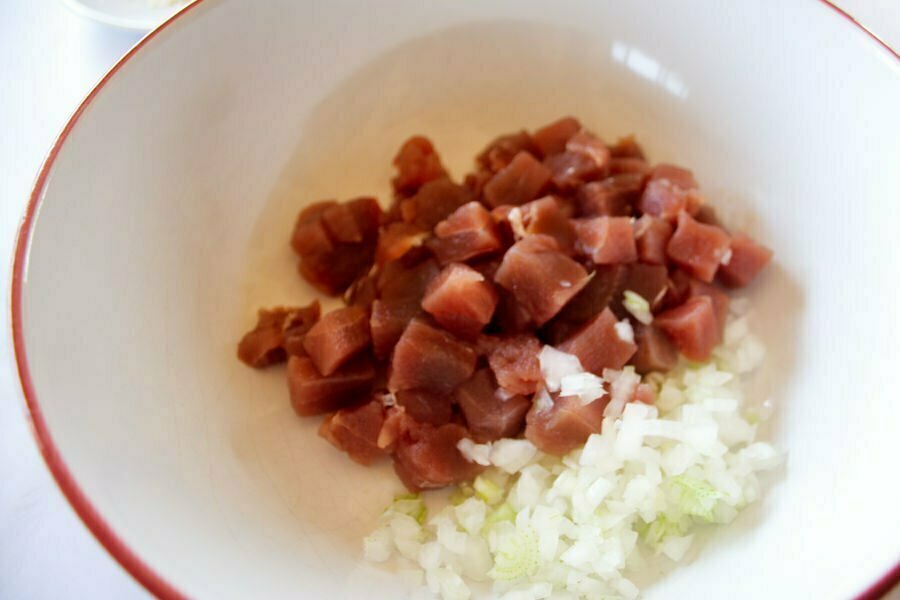 raw tuna is diced into small cubes alongside some finely diced white onion