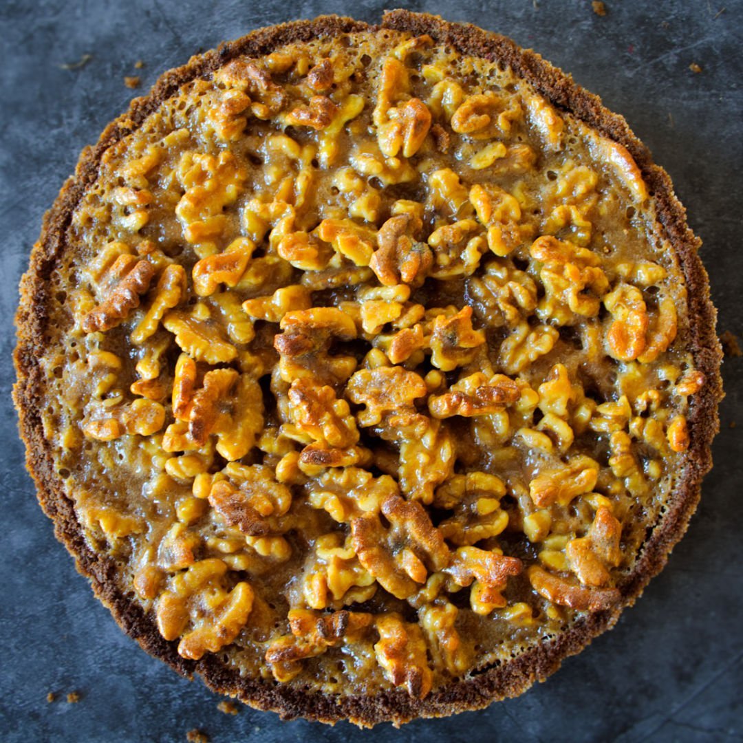 a. large walnut tart with orange-infused salted caramel sit on a counter waiting to be served. 