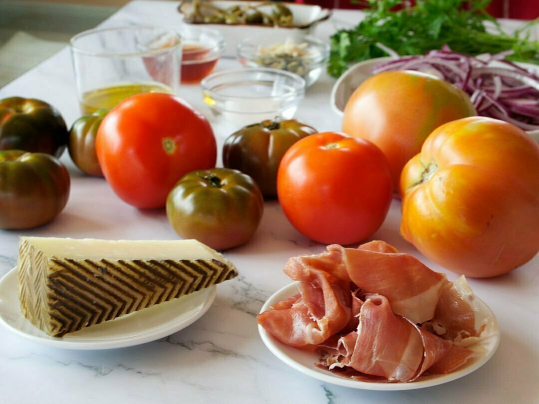 Ingredients for a Mediterranean tomato salad sit on a granite countertop