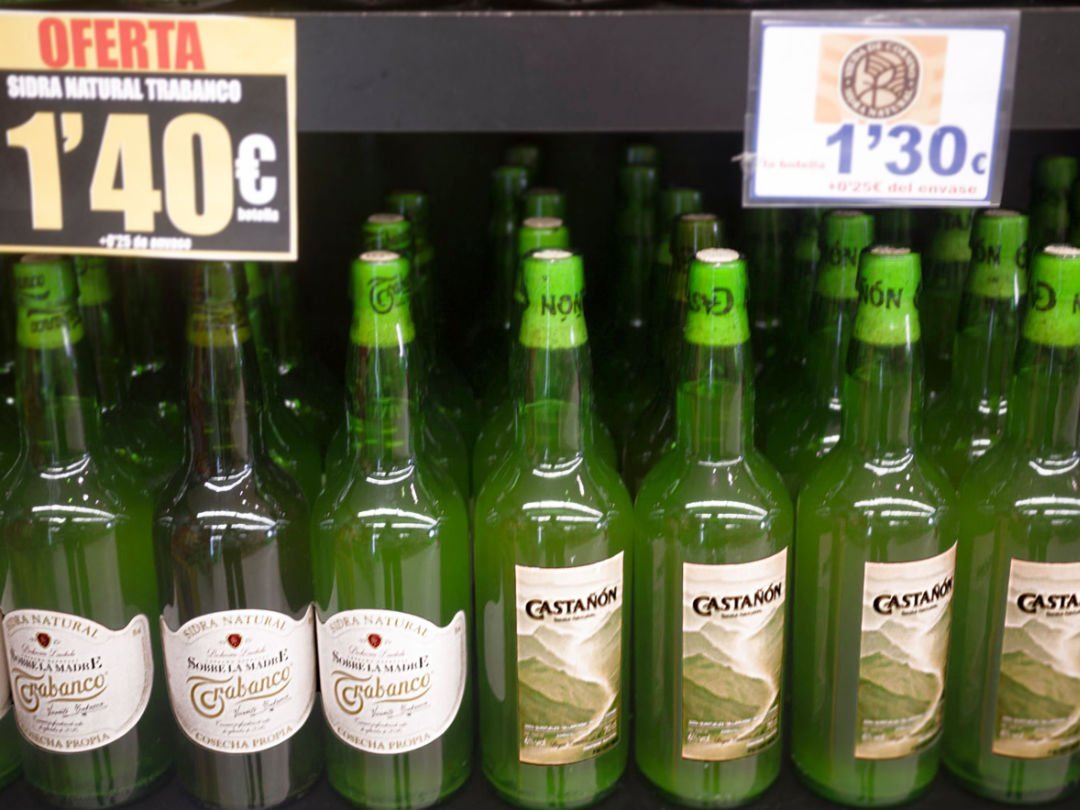 Asturian cider bottle sit in a shop with price tags above