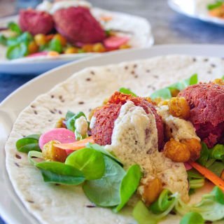 oven baked beetroot falafels are laid out on a bed of salad greens in a wrap