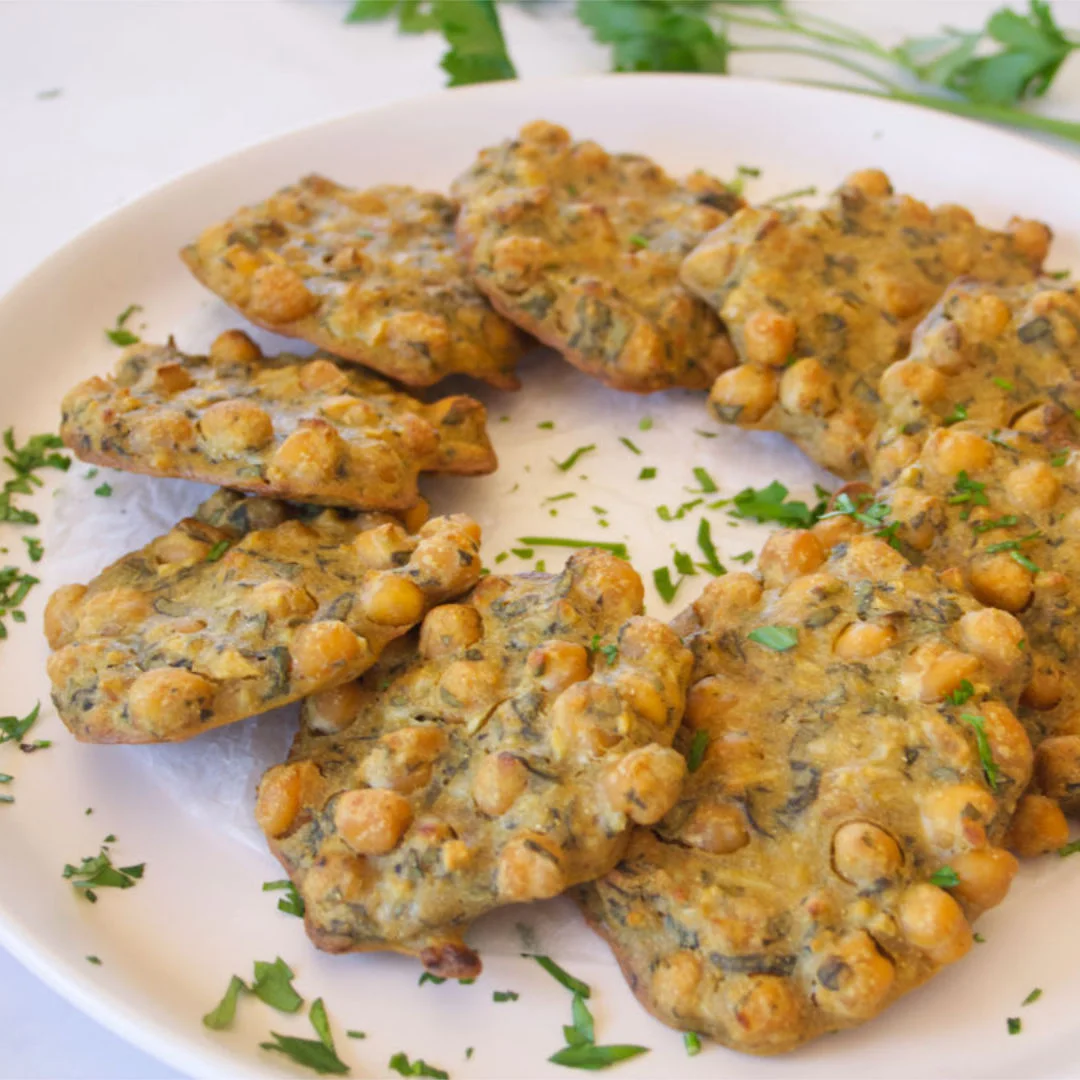 a large platter of chickpea fritters with some cilarntro and parsley sprinkled on top