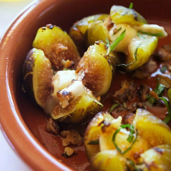 Fresh grilled figs with goats cheese and drizzled with honey are in a ceramic bowl