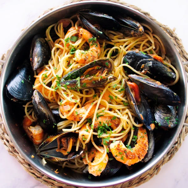 A large stainless steel pot full of shrimp and mussels pasta