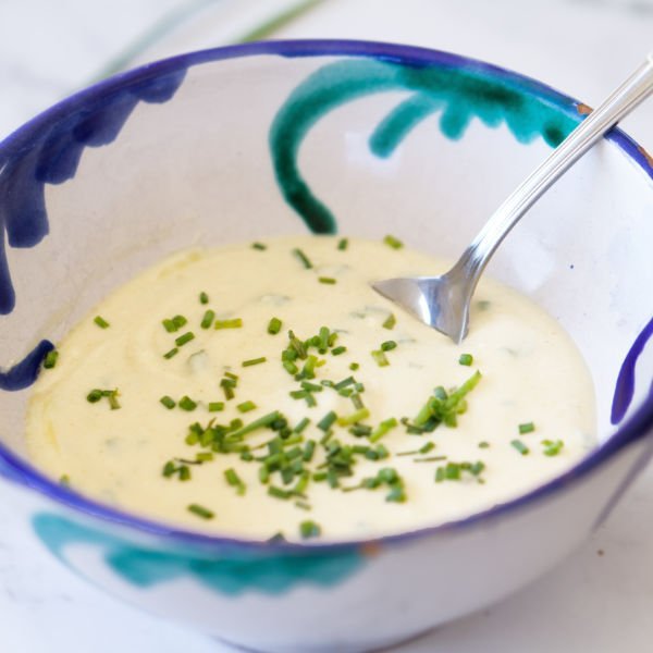 a small decorative bowl of yogurt salad dressing garnished with chives