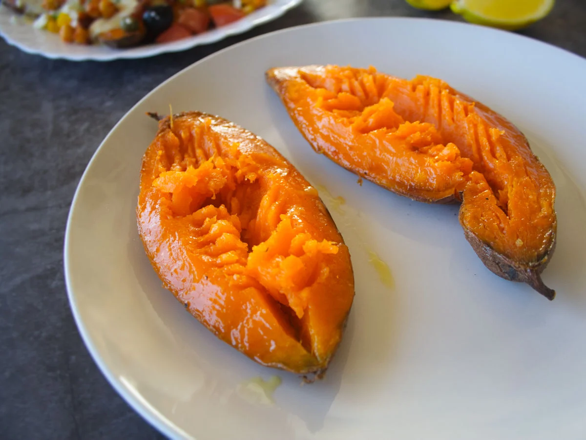 two baked sweet potato halves sit on a white plate