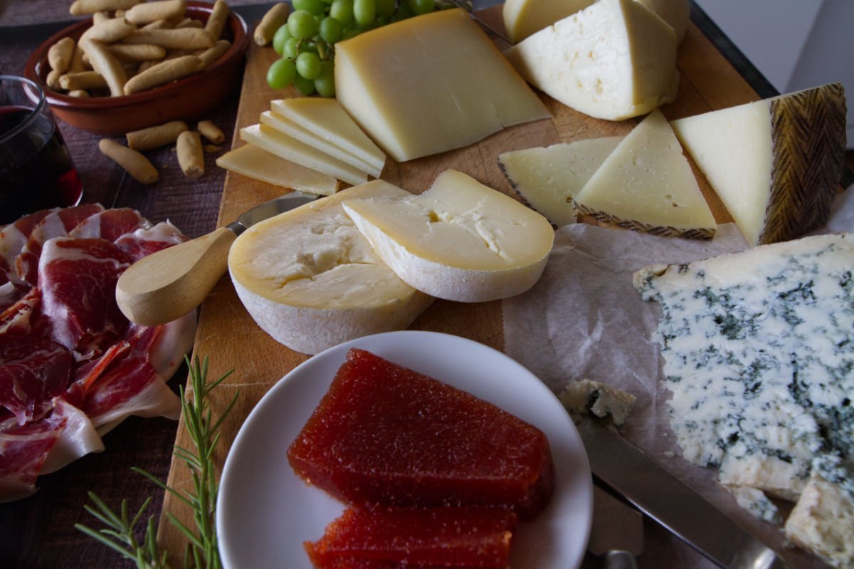 A large Spanish cheese board is laid out with various types of ccheese and other snacks