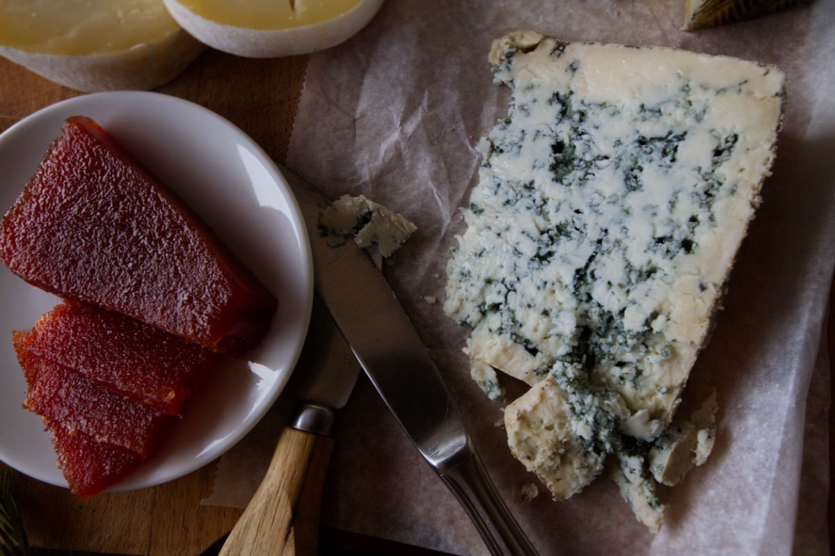 A larg wedge of cabrales cheese sits beside some quince paste