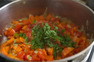spices and some fresh parsley are added to a pot of simmering vegetables