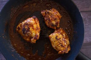 3 cooked chicken thighs sit in a frying pan