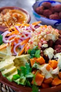 A beetroot falafel rice bowl sits with salad and other toppings