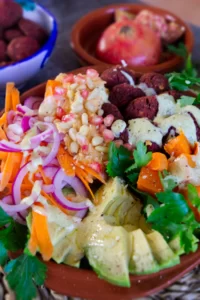 A beetroot falafel rice bowl sits with salad and other toppings.