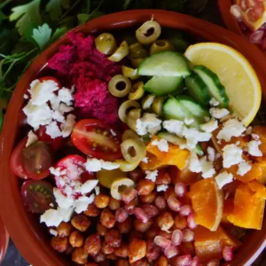A Mediterranean rice bbowl sits with lots of salad toppings