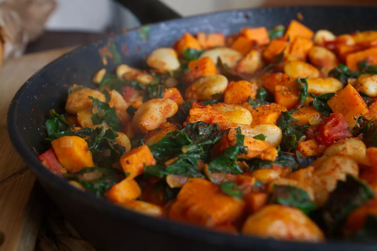 butter beans stew with sweet potato and kale sits in a large pan waiting to be served. 