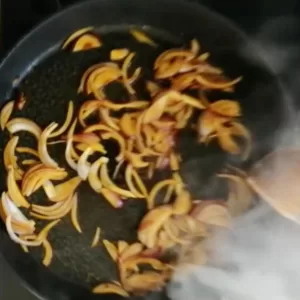 some fried red onnion slices cooks in peach juices