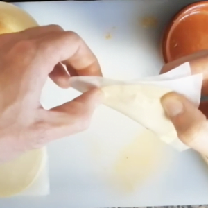 a person crimps the edges of an empanada with their hands