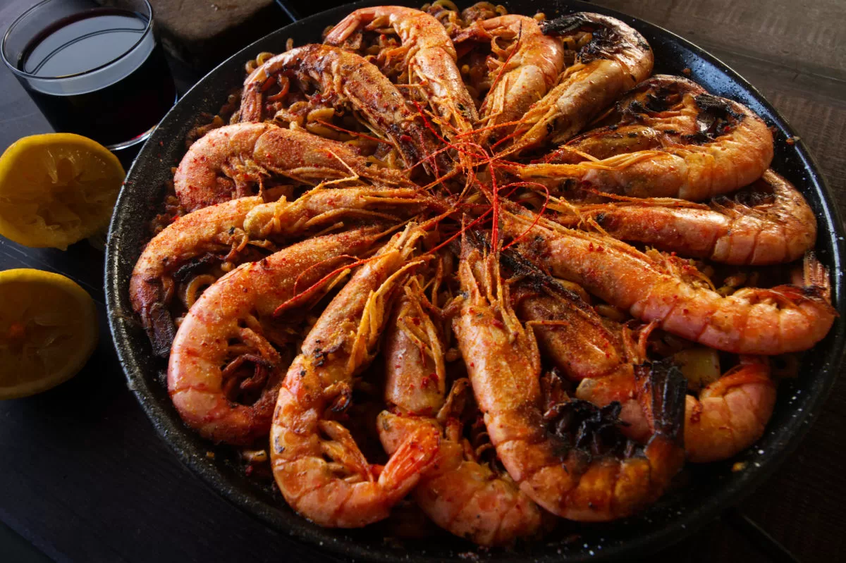 a large pan of Spanish fideua marisco is topped with lots of cooked shrimp