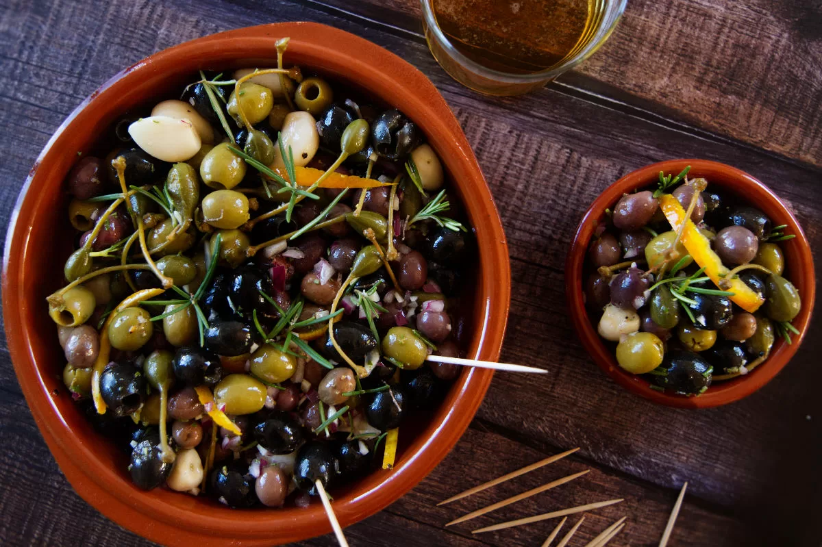 a large bowl of spanish style marinated olives sits on a small countertop