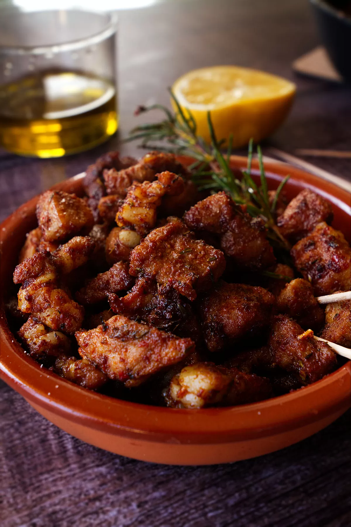 a small bowl of paprika-infused pork bites sits beside a small glass of sherry