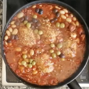 Olives are added to a pan of Spanish Chicken with cchorizo and wine