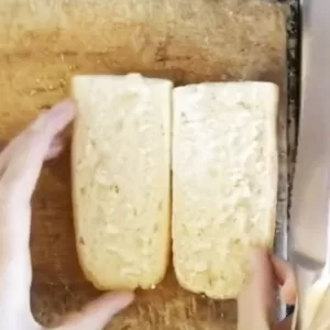 A baguette is sliced in half and into 8 inch portions