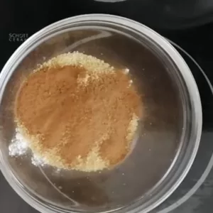 Sugar, cinnamon, and flour are added to a glass bowl.