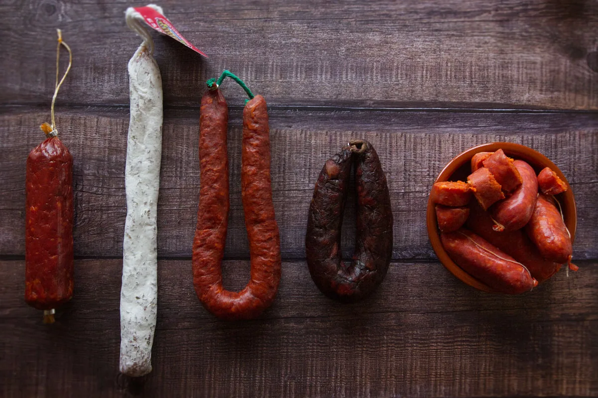 Differnt types of Spanish chorizo sit on a wooden kitchen counter