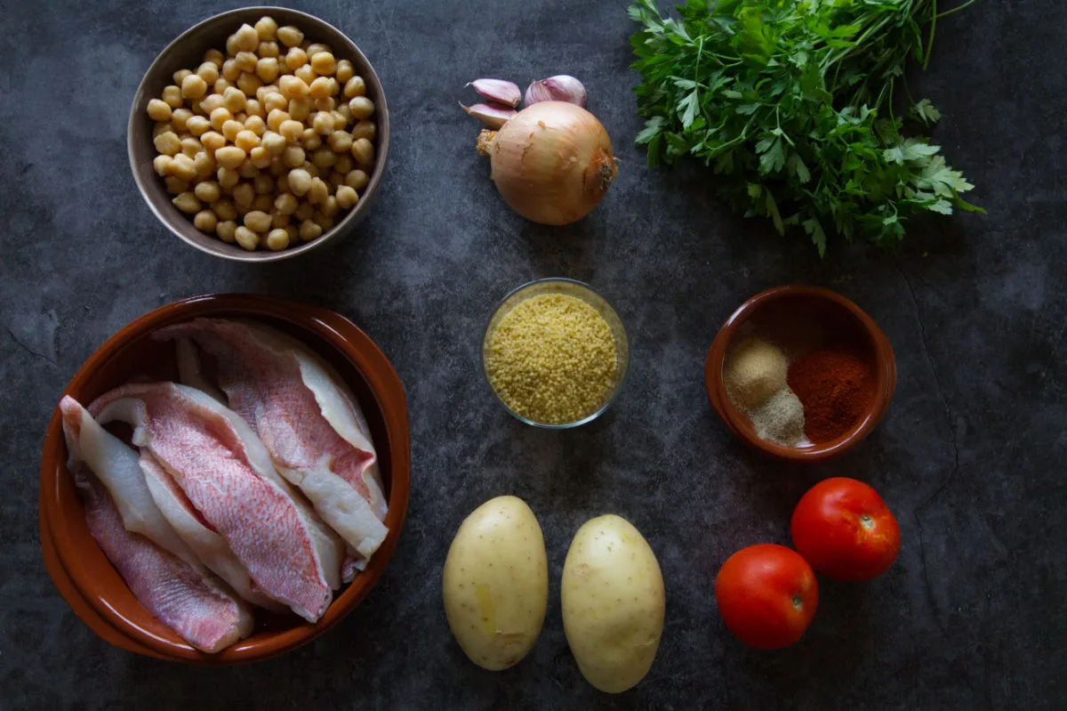 ingredients for making a fish stew with chickpeas, maravilla pearl pasta, and spicces all sit on a counter top. 